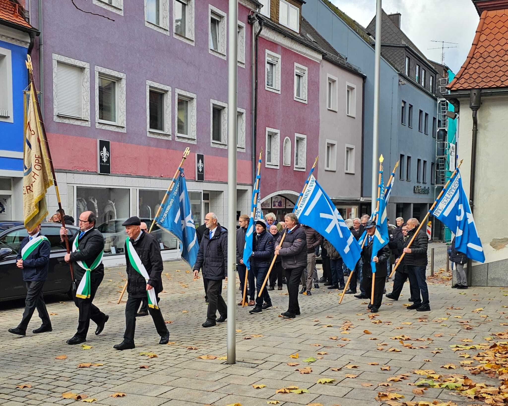 Sodalen mit wehenden Fahnen bei böigem Wind zu den Klängen der Blasmusik und großem Orgelgeläute