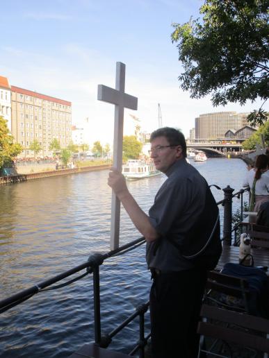 Pater Markus hält den Gegendemonstranten das Kreuz entgegen